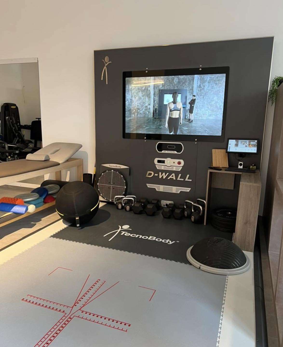 La postazione D-WALL TecnoBody dello studio: schermo per l'analisi del movimento, pesi, bosu e tappetino con reticolo di misurazione